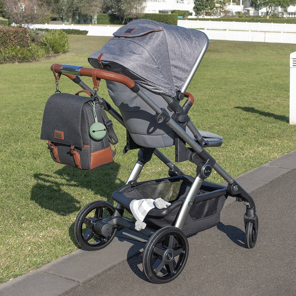 Gray stroller with a bag on a grassy area