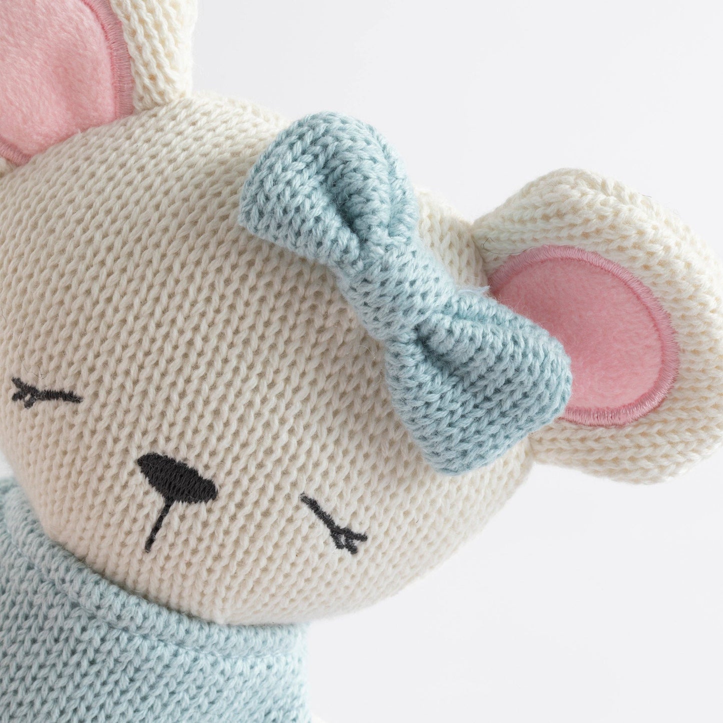 Knitted toy with a face, ears, and bow on a white background