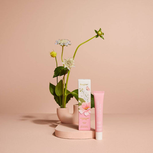 Pink skincare tube and box with flowers on a beige background