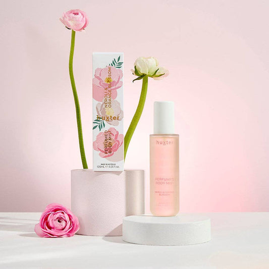 Nuxe body care product with flowers on a pink background