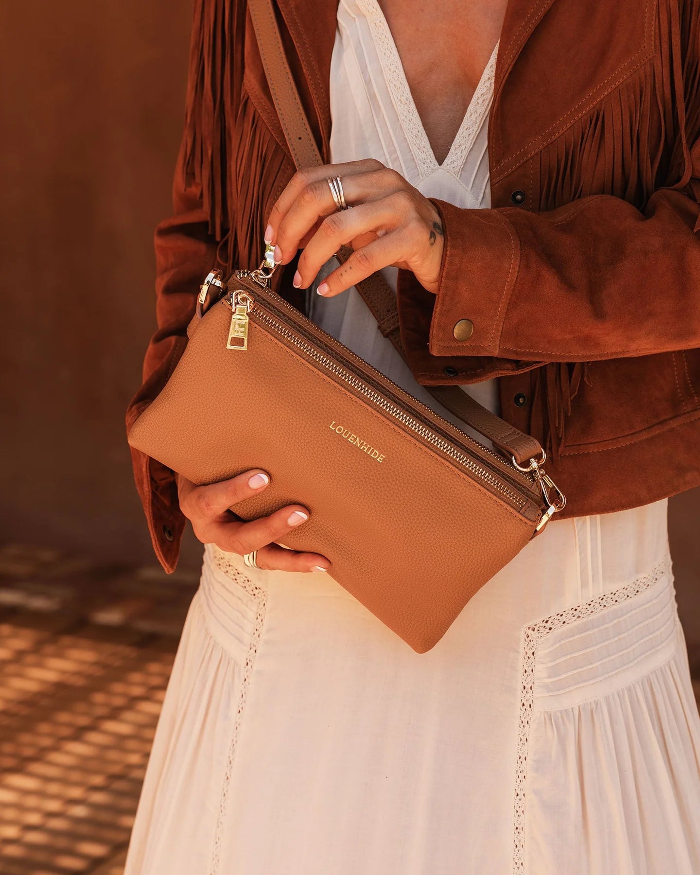 Person holding a brown leather bag boho style