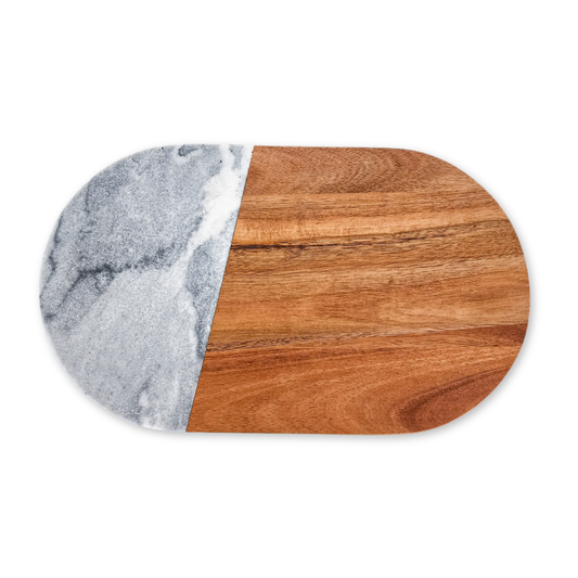 An oval-shaped cheese board made of grey marble and acacia wood, with the marble forming the top left corner and the wood the remaining right three-quarters.