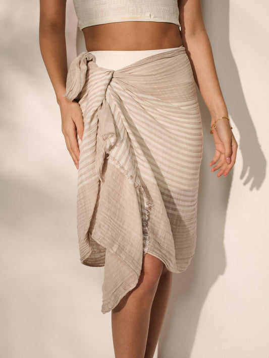 Person wearing a beige wrap skirt on a plain background