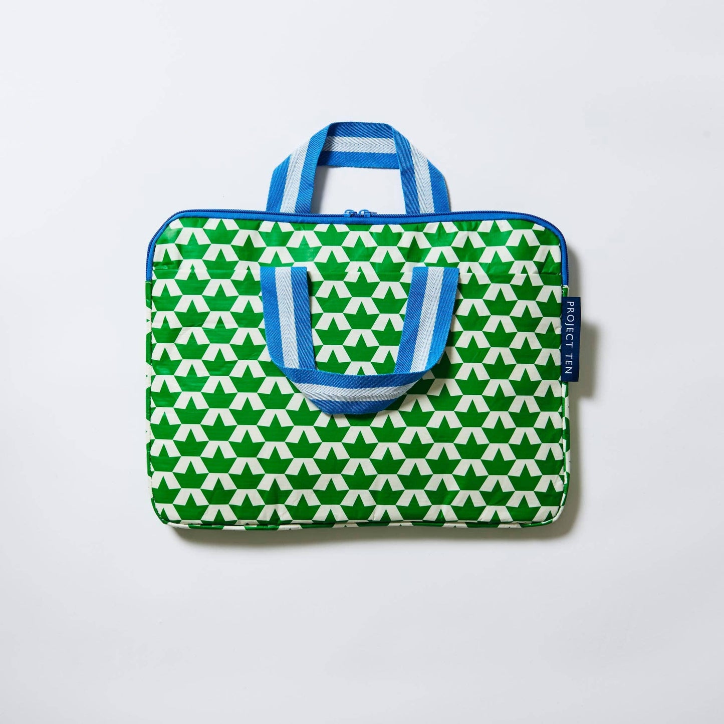 Green and white patterned bag with blue handles on a light gray background