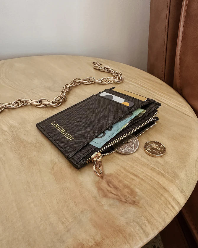 Black wallet with gold chain on a wooden surface