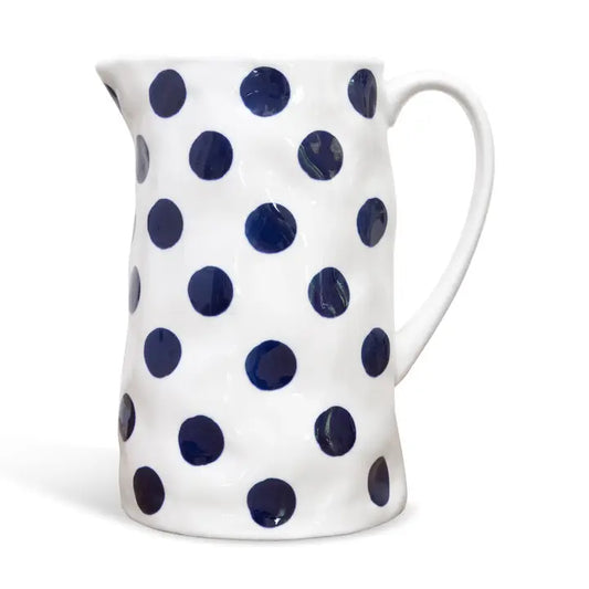 White ceramic pitcher with blue polka dots on a white background