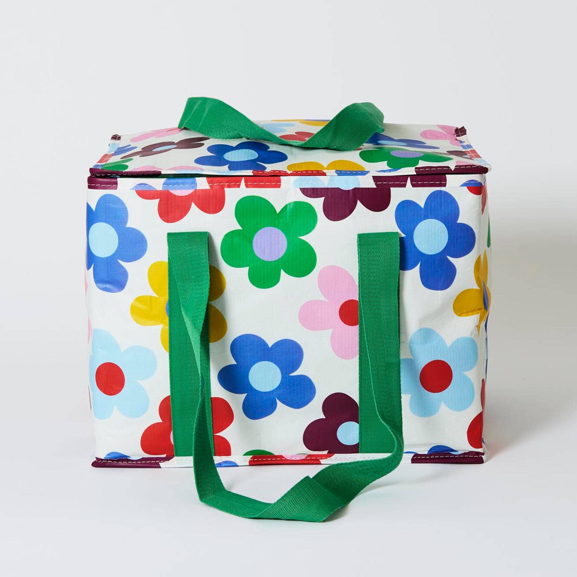 Colorful floral-patterned bag with green handles on a white background