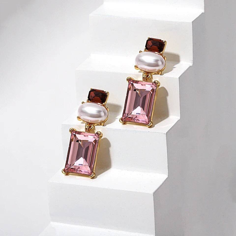 Pair of earrings with pink gemstones and pearls on a white background