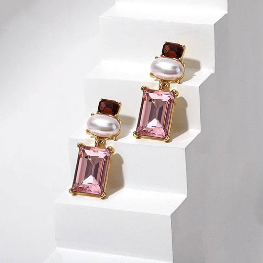 Pair of earrings with pink gemstones and pearls on a white background