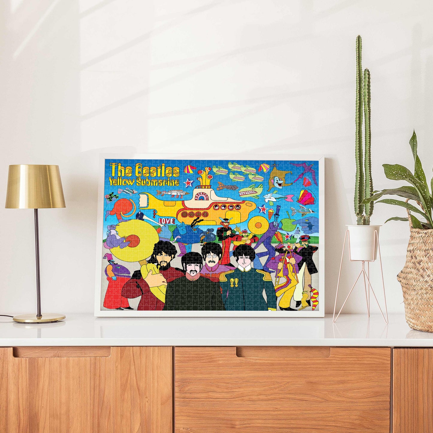Framed poster of The Beatles' 'Yellow Submarine' on a white wall above a wooden cabinet.