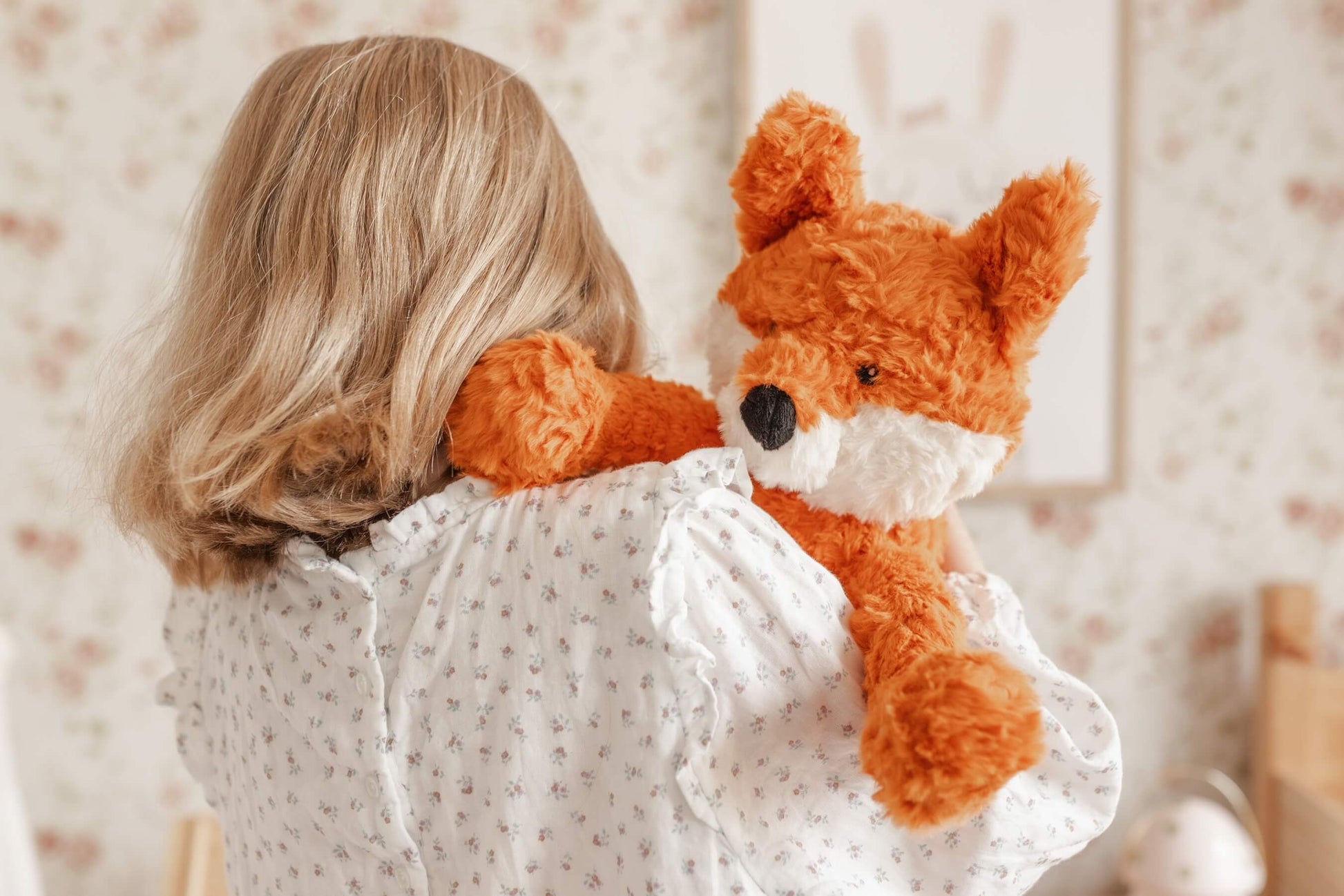 Child holding a plush fox toy in a softly lit room