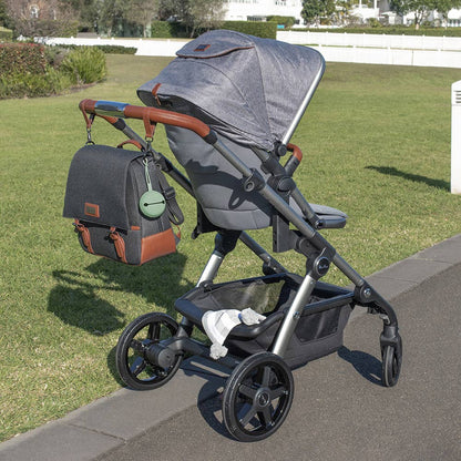 Gray stroller with a bag on a grassy area