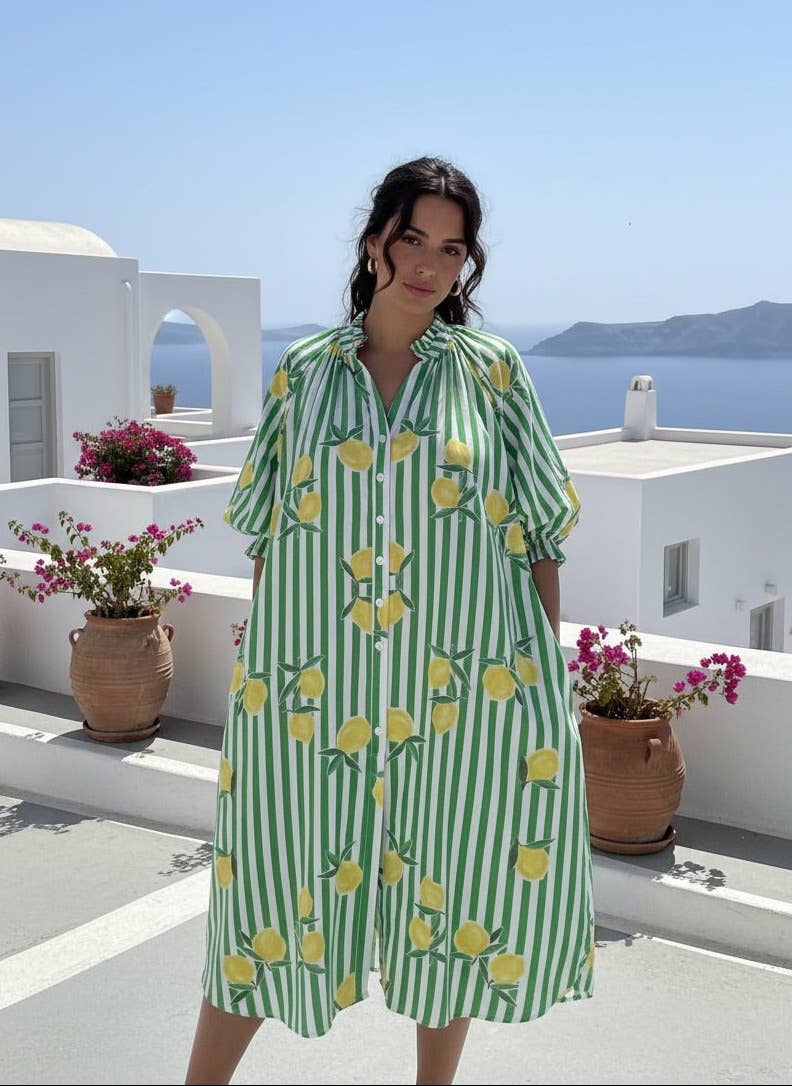 Woman wearing a green and white striped dress with lemon pattern on a rooftop with ocean view.