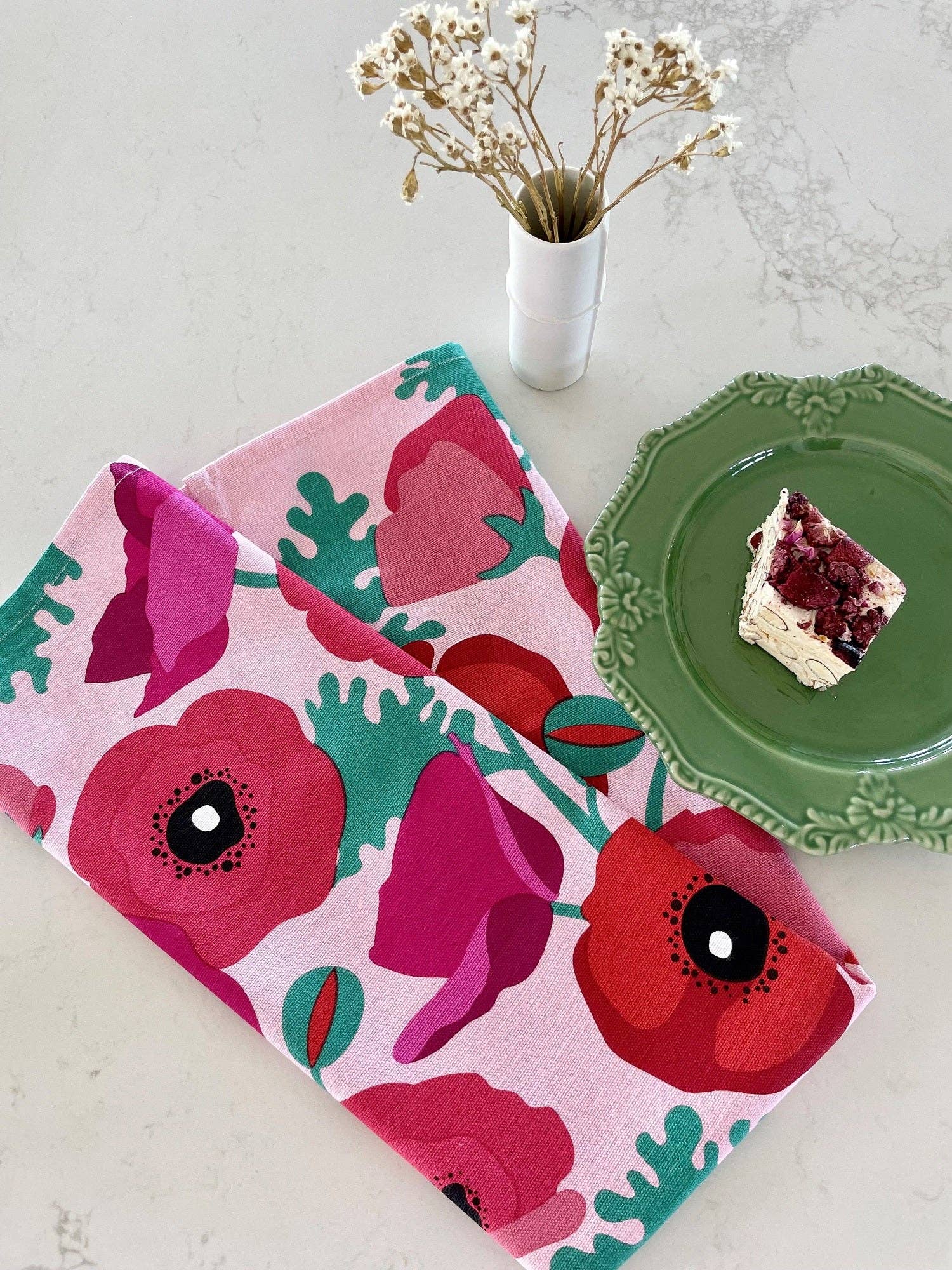 Floral-patterned towel on a table with a green plate and dessert