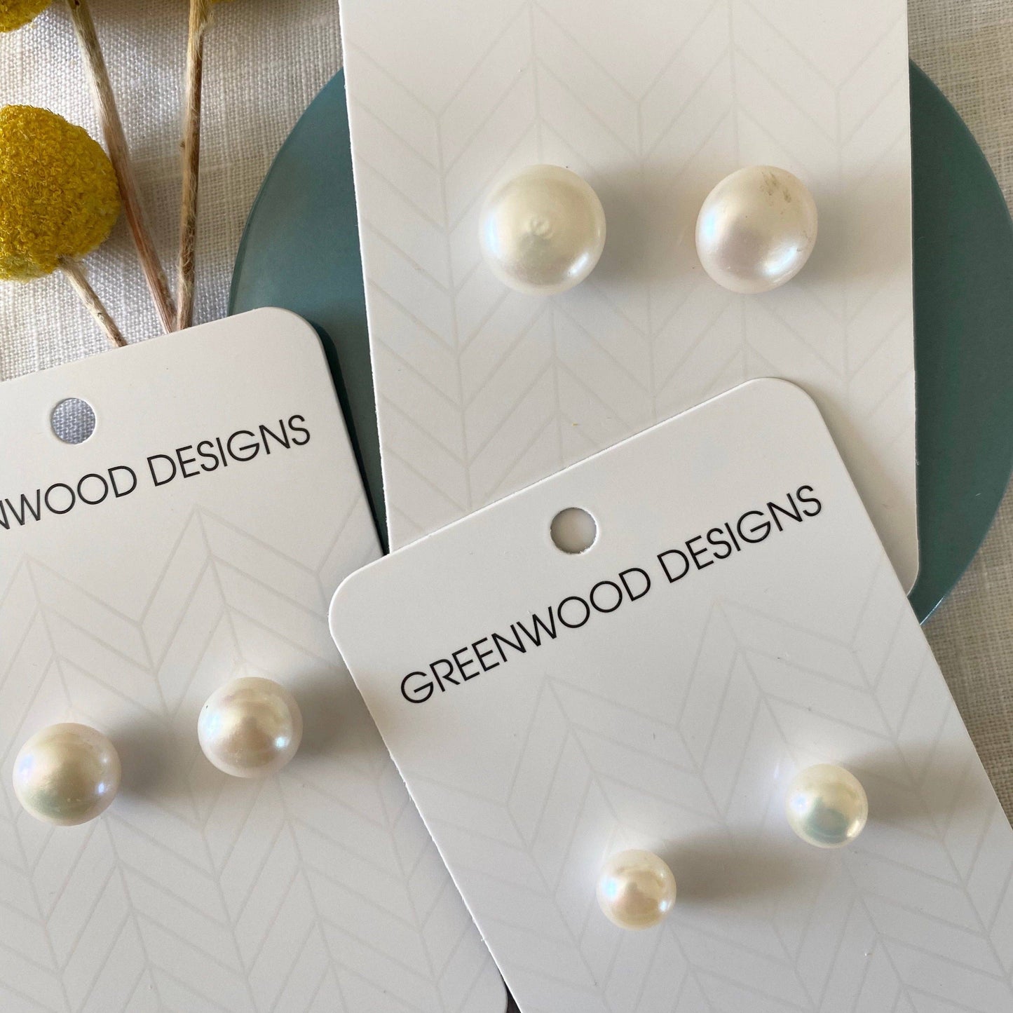 Pearl earrings on Greenwood Designs display cards with a neutral background.