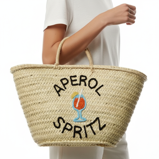 Woven bag with 'Aperol Spritz' text and logo held by a person wearing a white outfit.