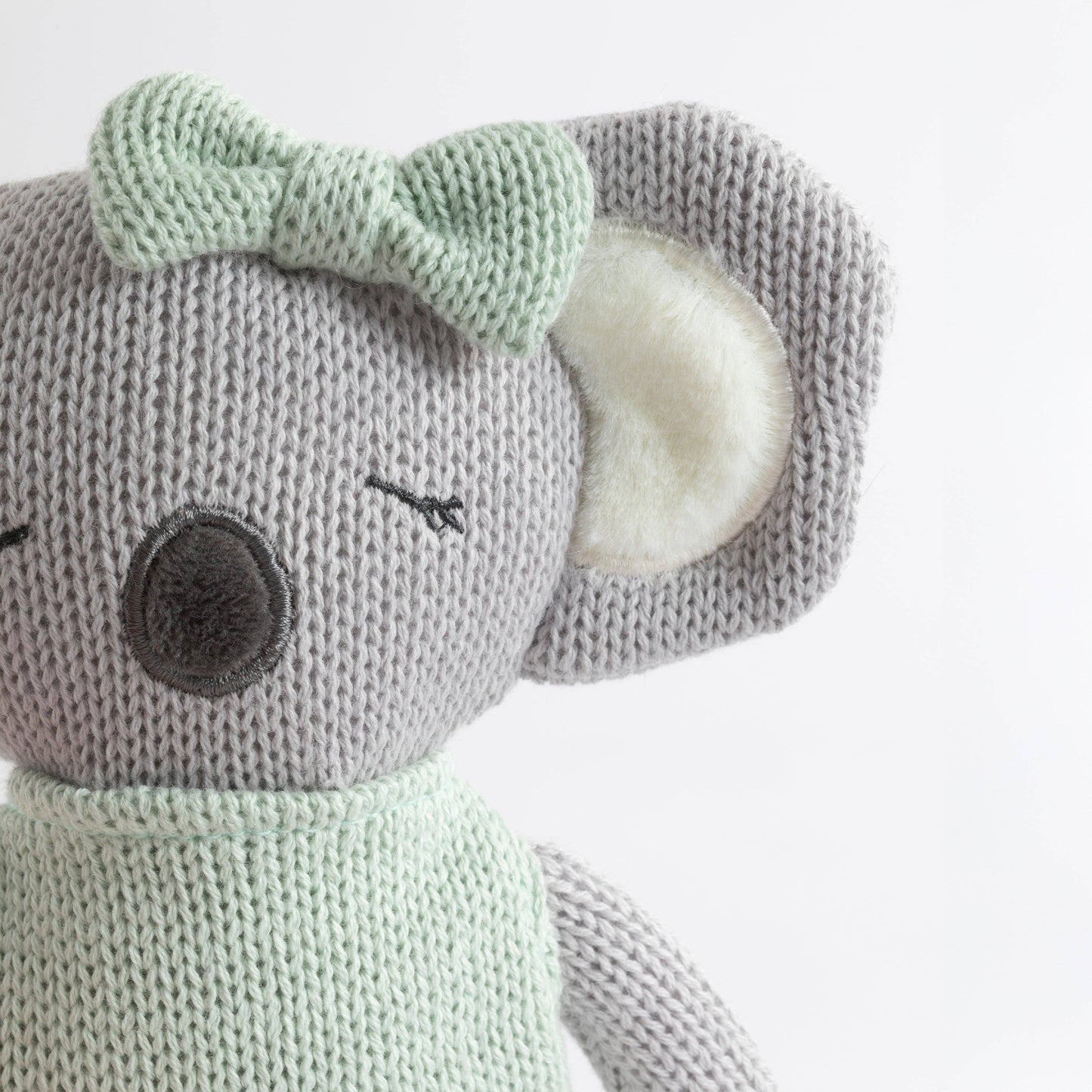 Knitted toy mouse with a green bow on a white background