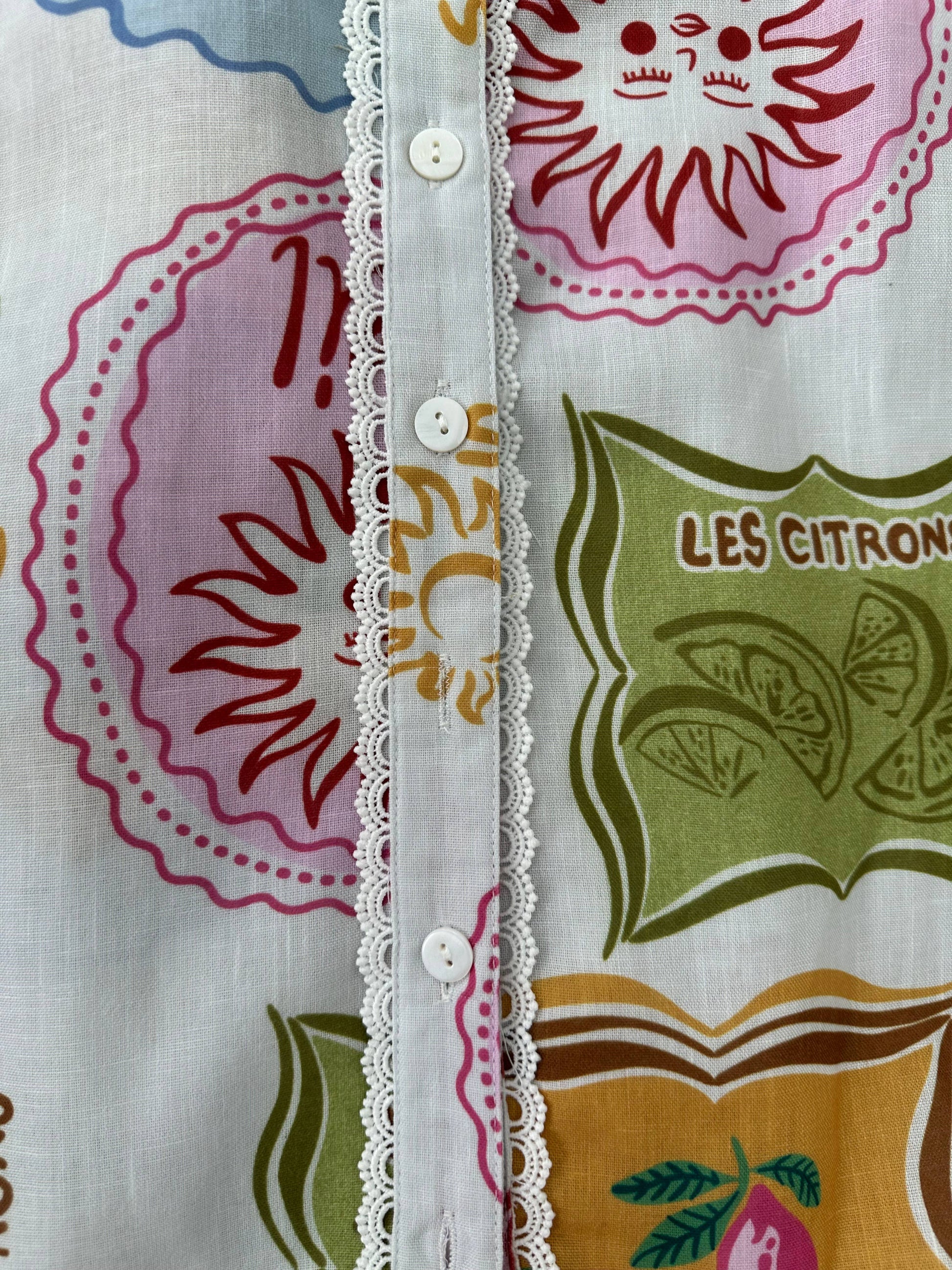 Close-up of a fabric with colorful patterns and text, featuring a floral design and 'Les Citron' branding.