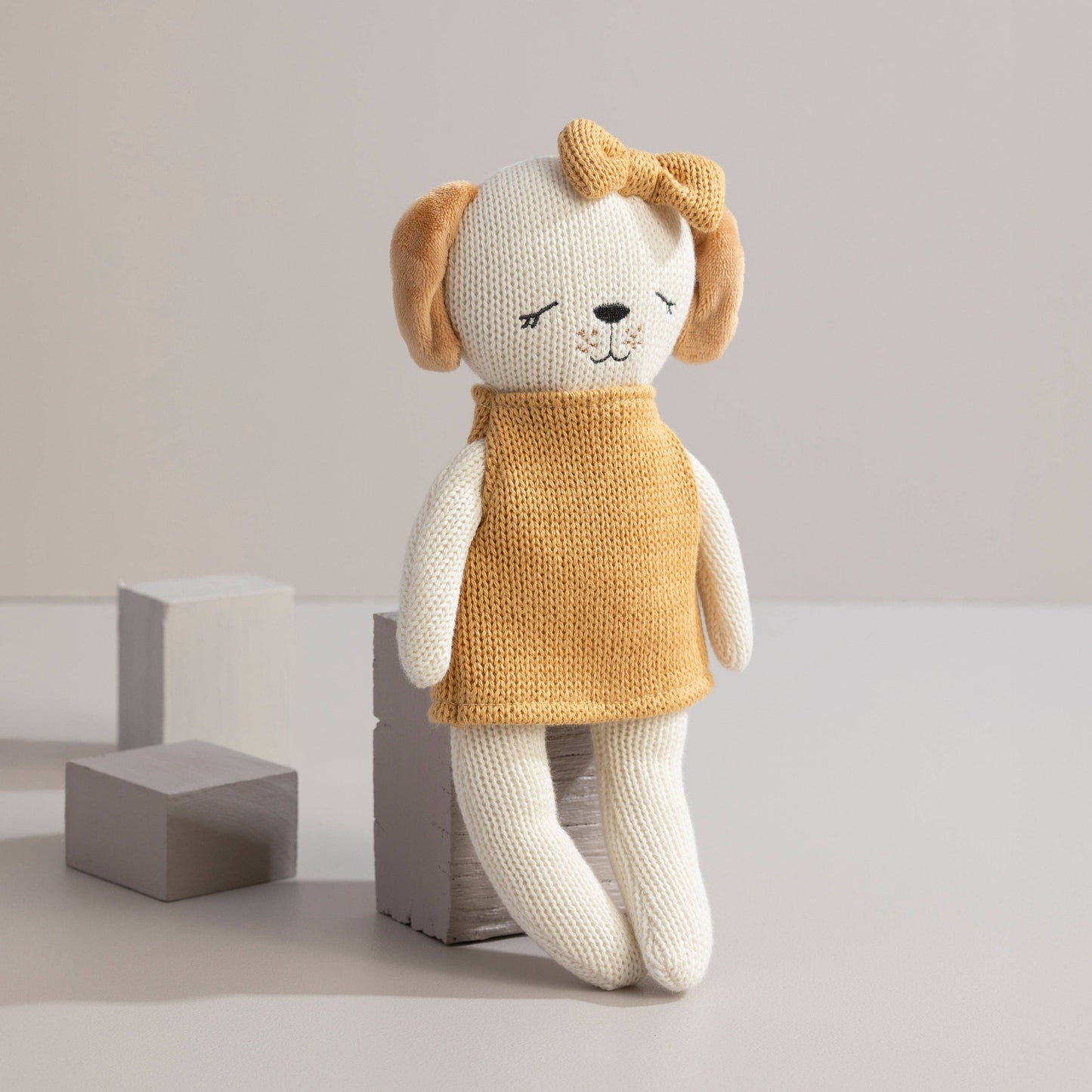 Knitted dog toy with a mustard yellow sweater on a light background