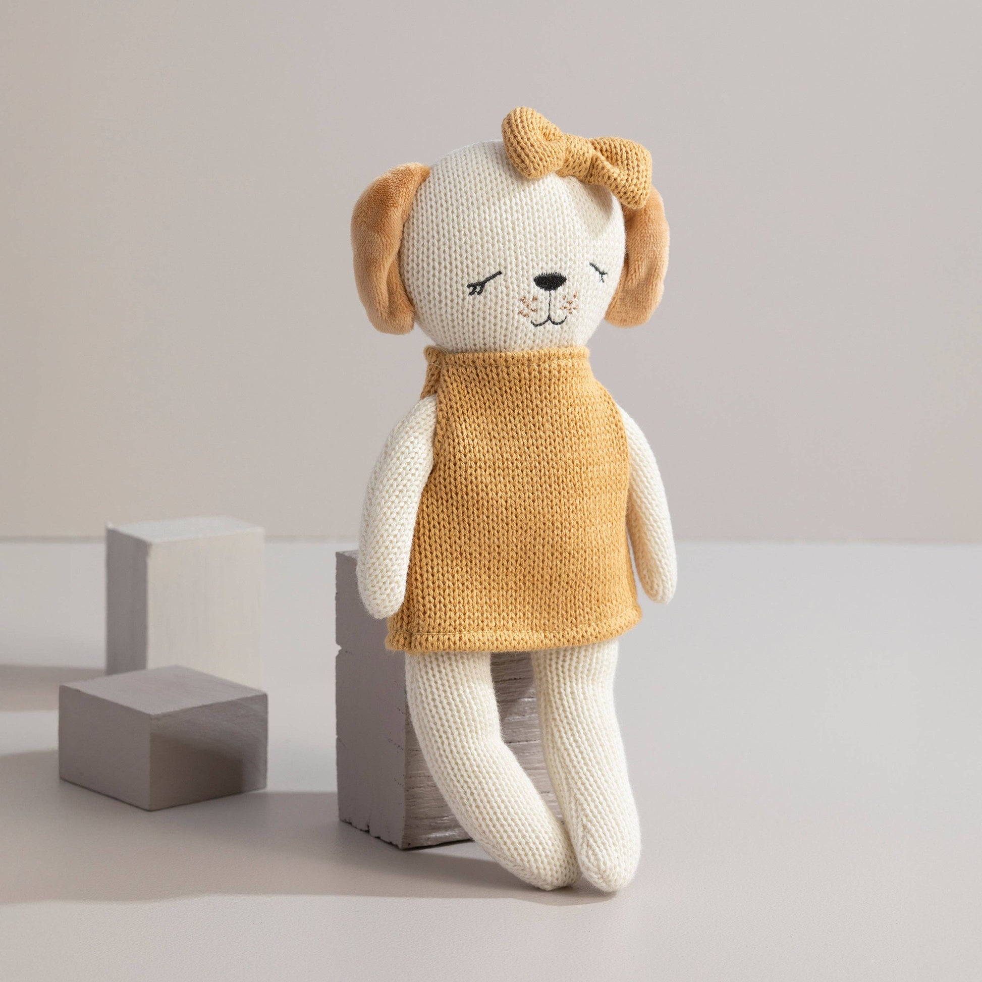 Knitted dog toy with a mustard yellow sweater on a light background