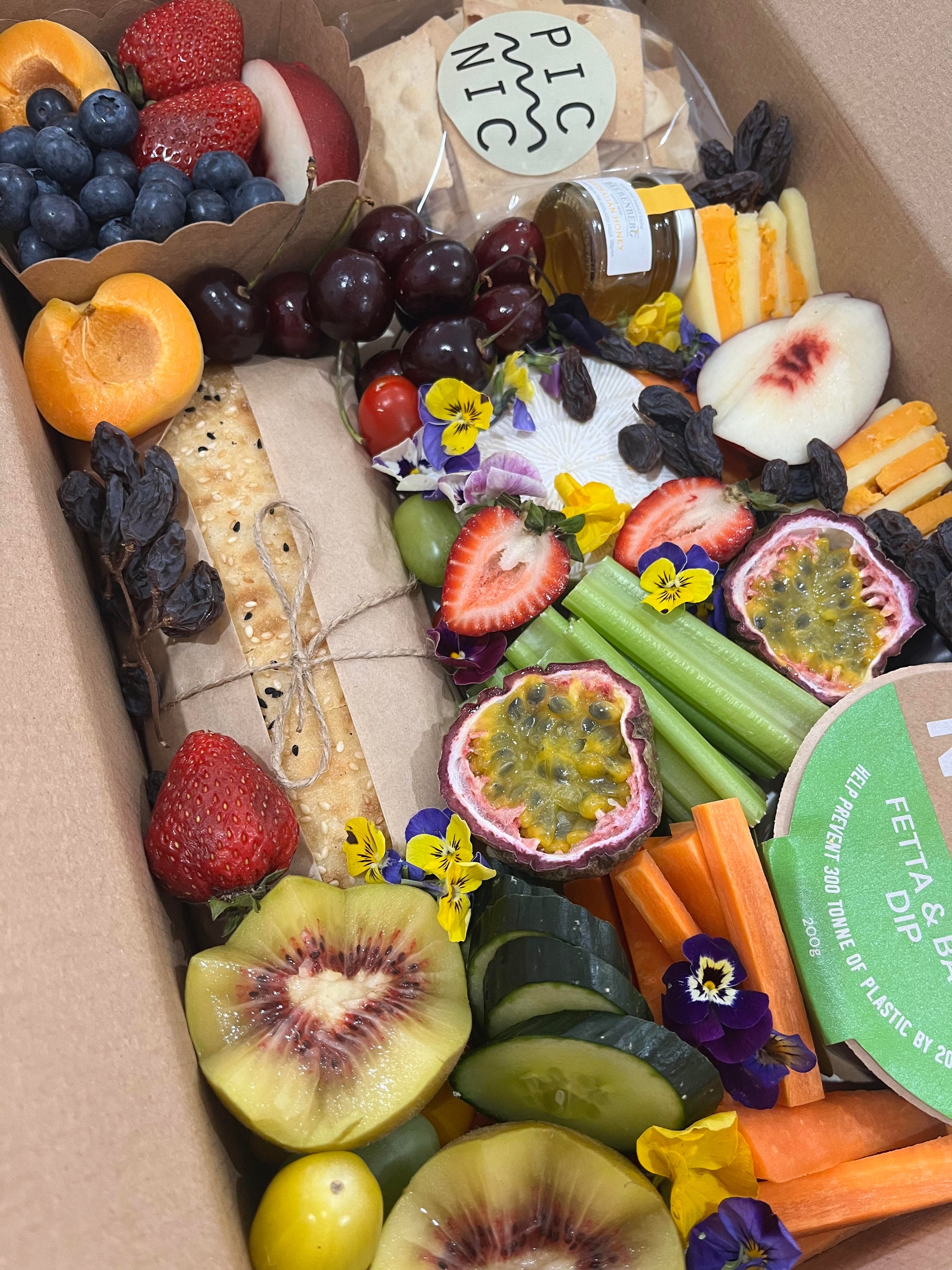 Assorted fruits, vegetables, and cheeses in a box labeled 'Picnic'.