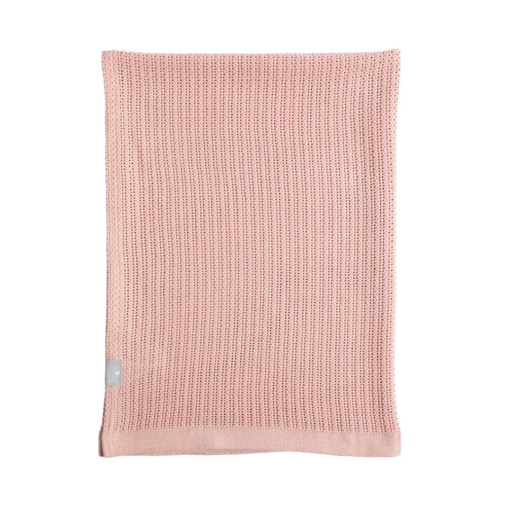 Pink knitted blanket with a small gray tag on a white background