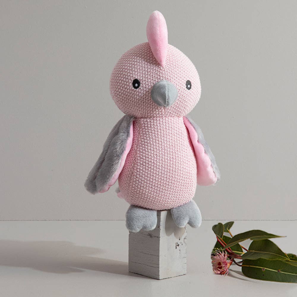 Pink and gray stuffed toy on a white surface with a light gray background