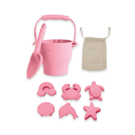 Pink sand pail, shovel, and beach molds with a mesh bag on a white background