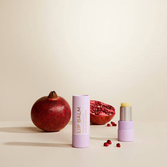 Lip balm with pomegranate seeds on a beige background