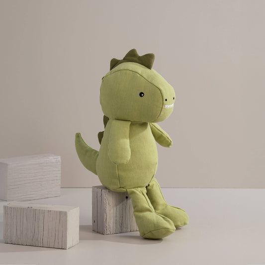 Green dinosaur plush toy on wooden blocks against a plain background