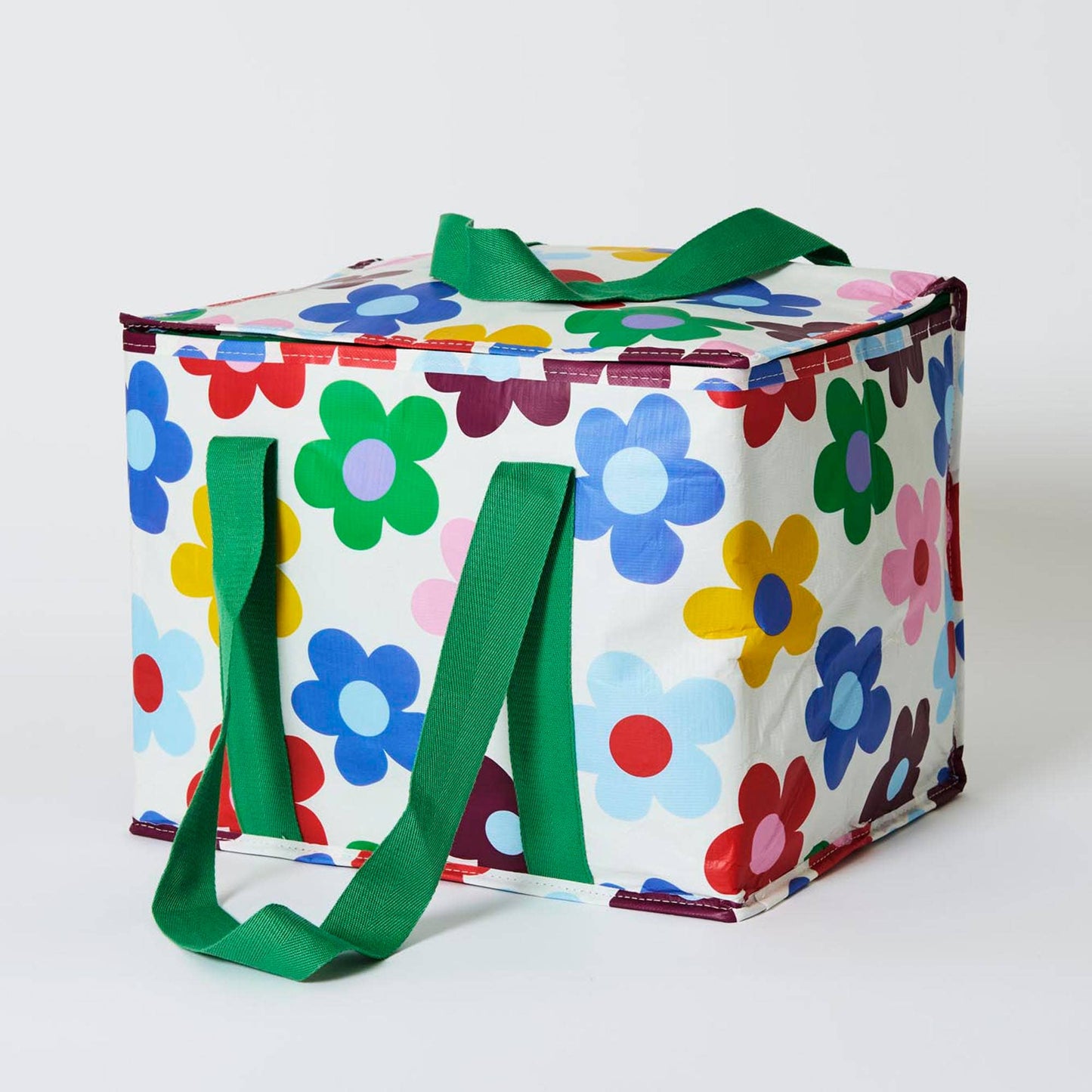 Colorful floral-patterned storage bag with green handles on a white background