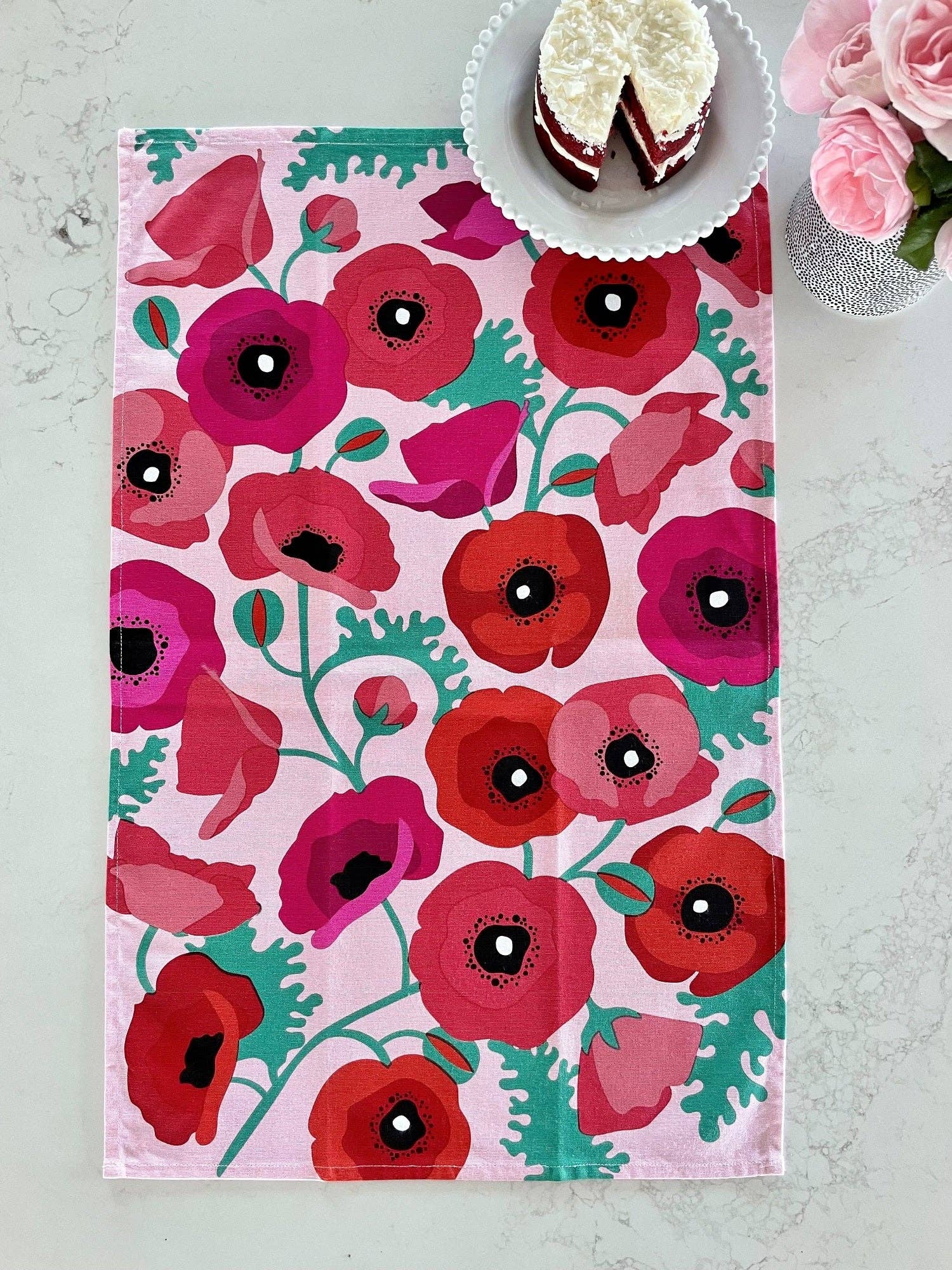 Floral-patterned tablecloth with red and pink flowers on a white surface.