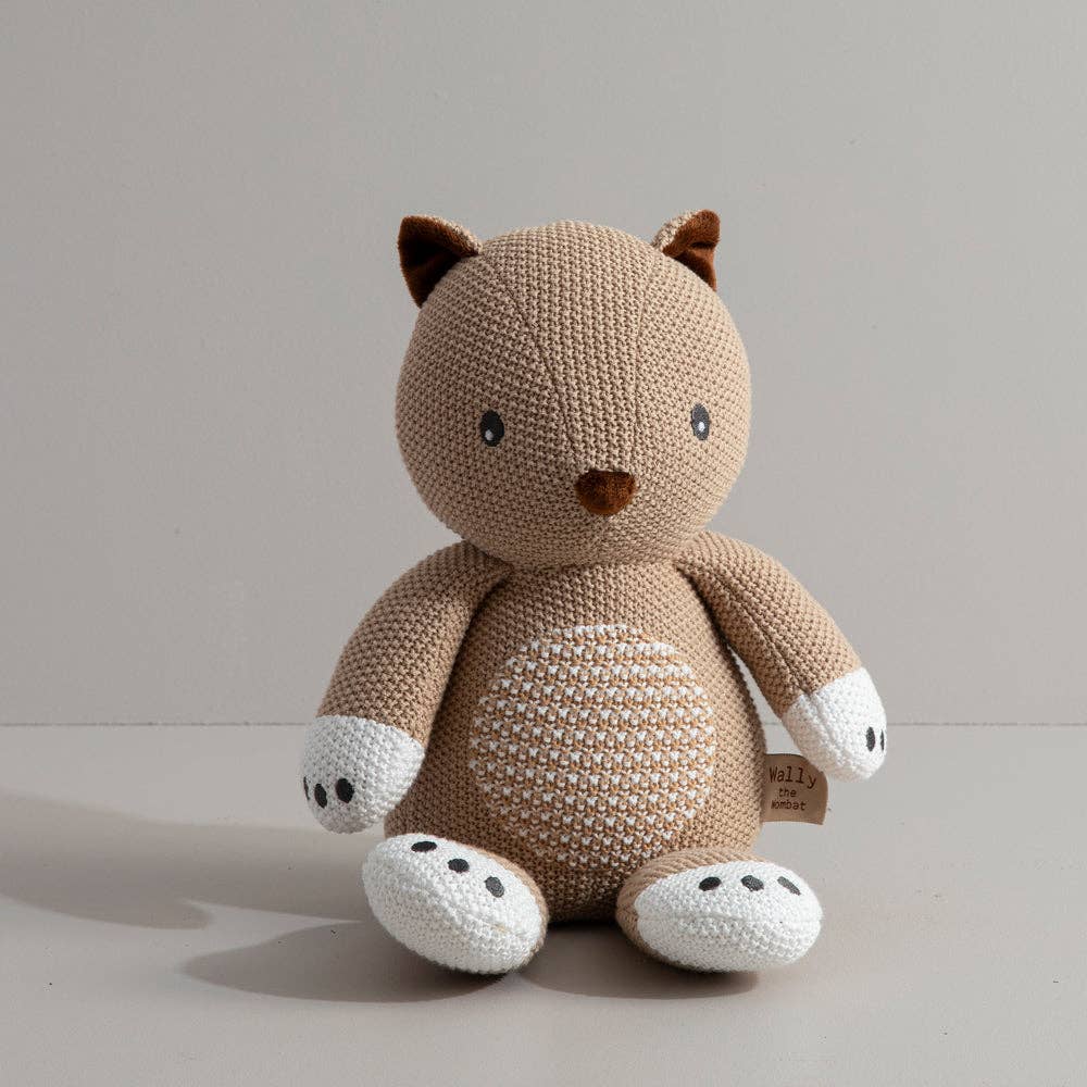 Knitted wombat toy with brown and white colours on a light grey background