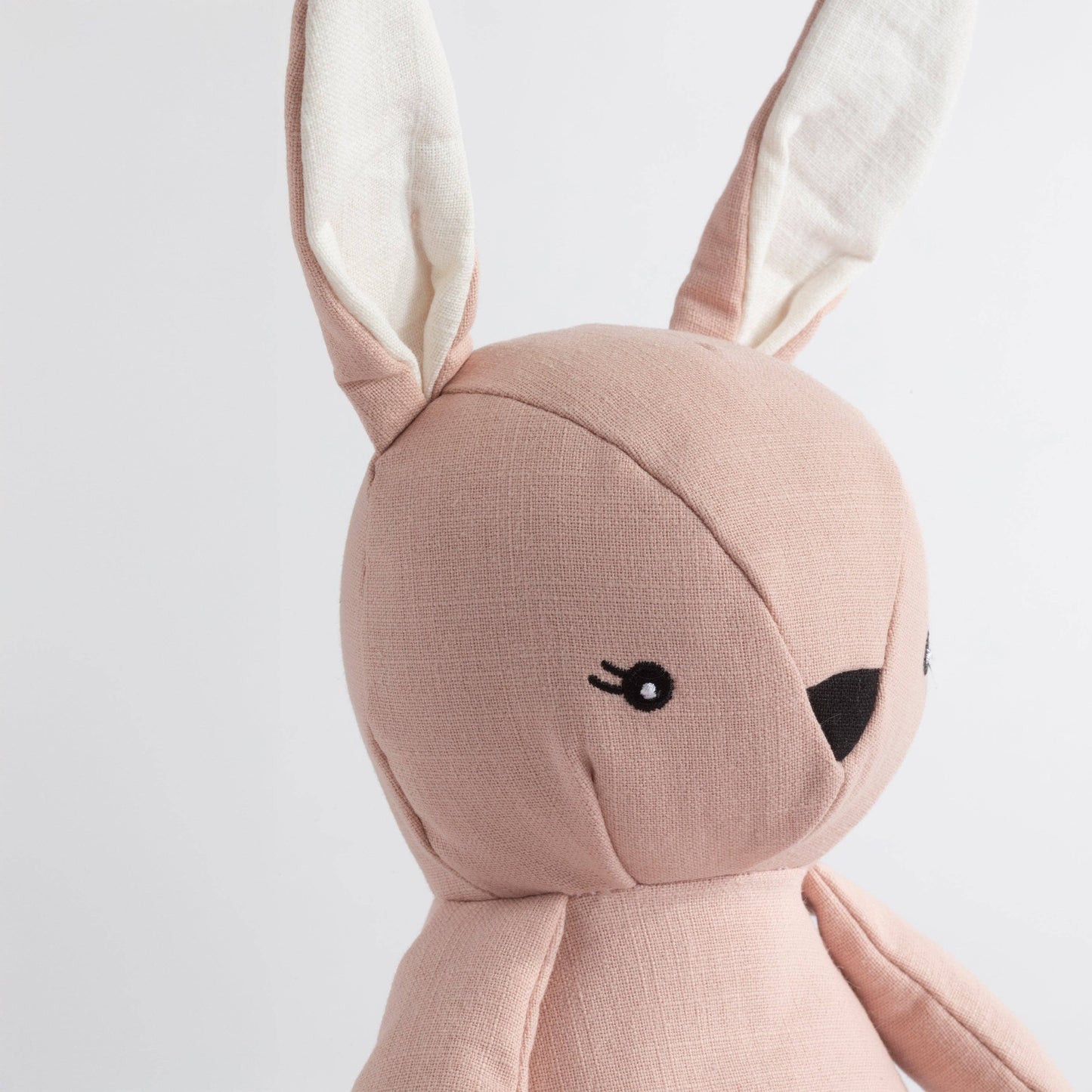 Pink plush toy with bunny ears on a light gray background