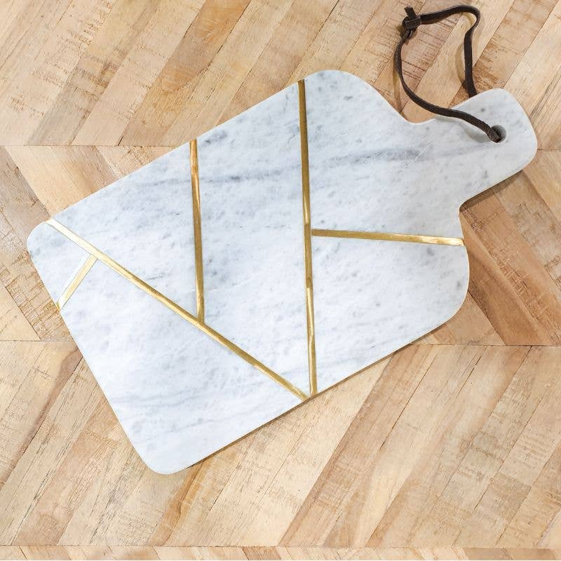 Marble cutting board with gold accents on a wooden surface