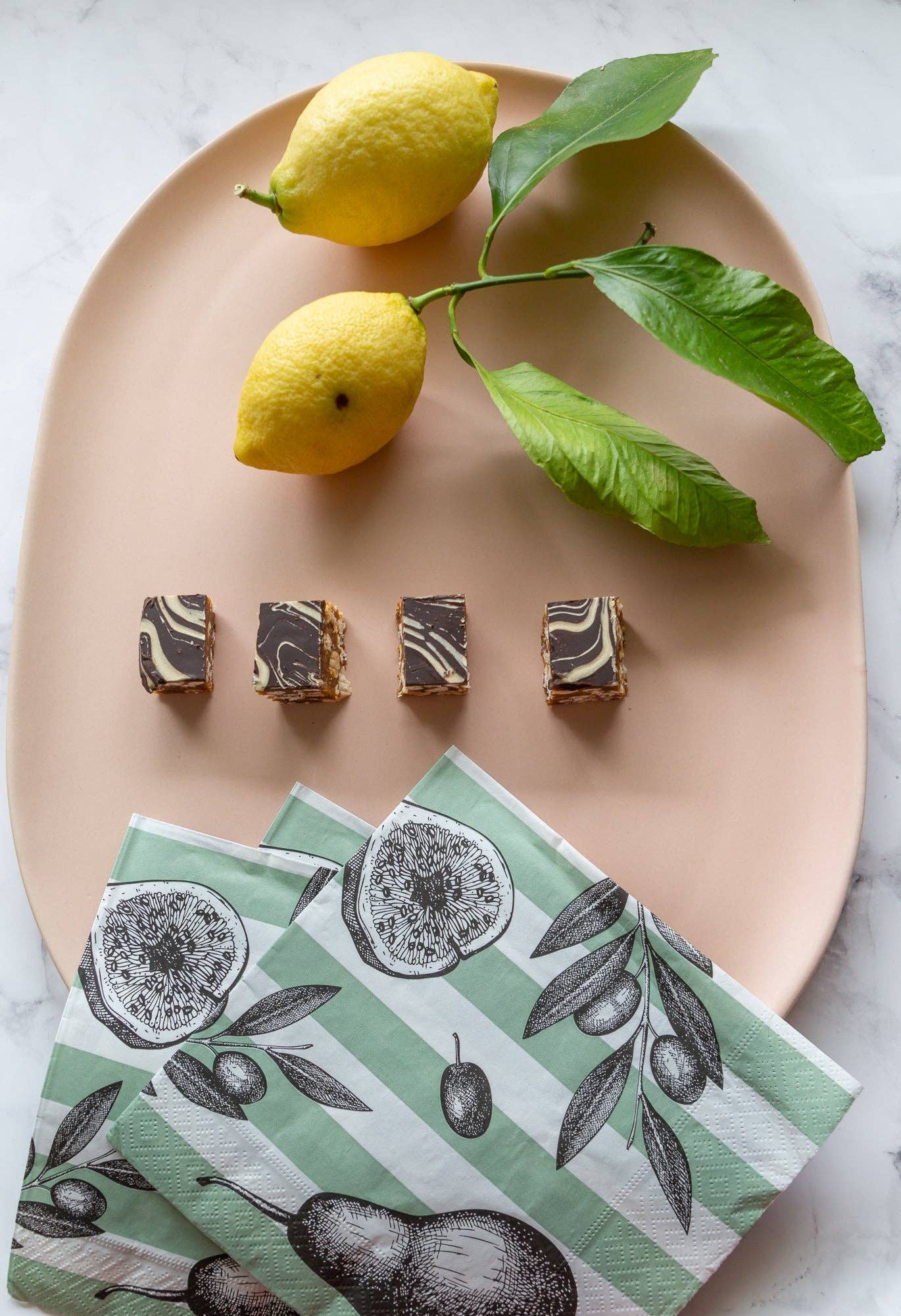 Napkins with fruit design on a plate with lemons and dessert.