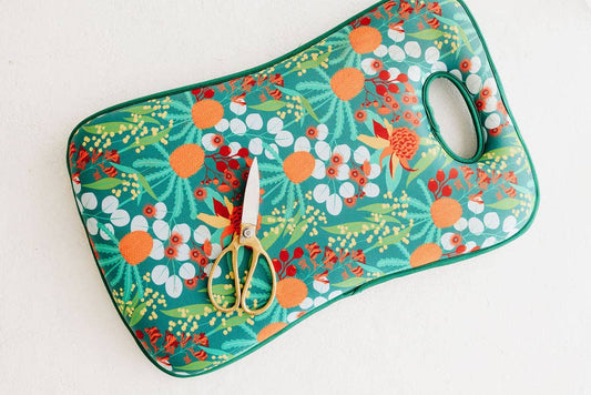 Floral-patterned cutting mat with scissors on a white background