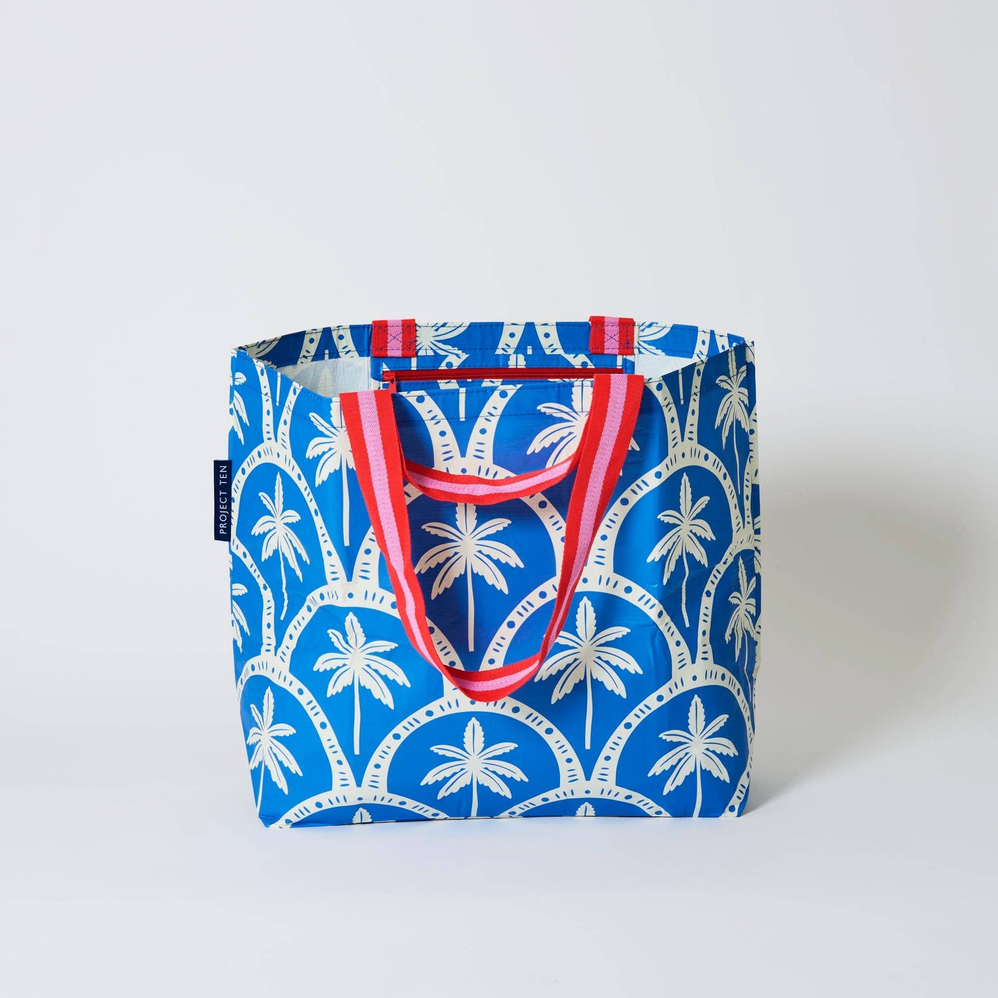 Tote bag with palm tree pattern and red handles on a white background
