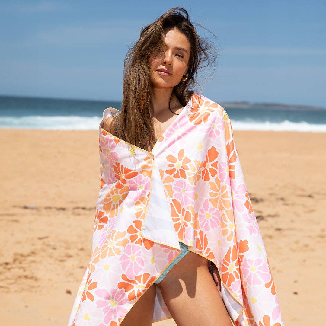 Woman on a beach wrapped in a floral towel with ocean in the background