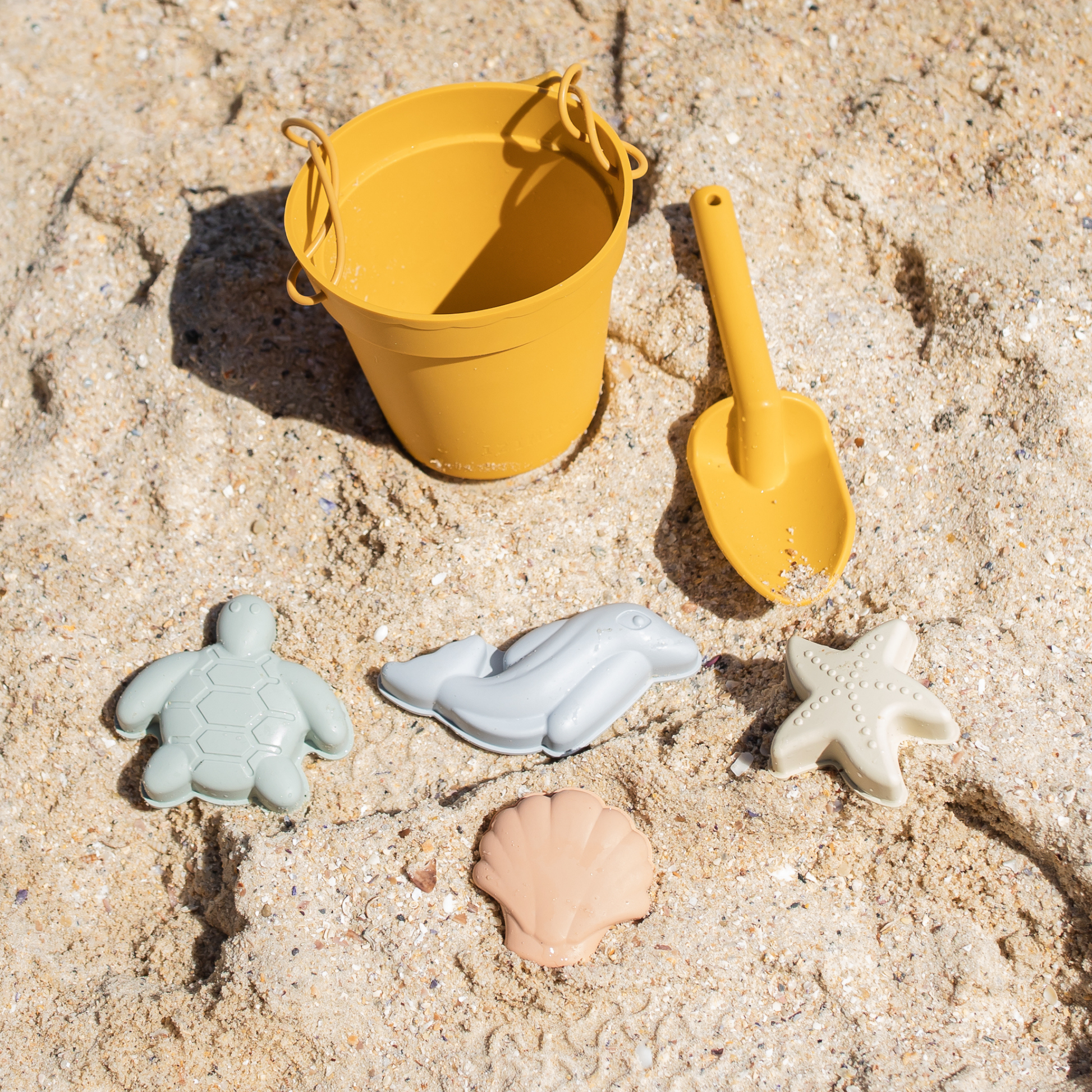 Yellow bucket and spade with sand toys on a sandy surface