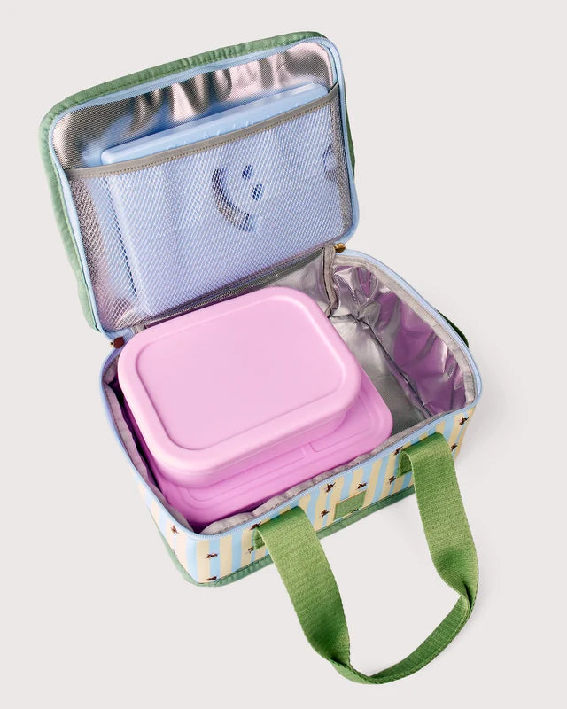 An open insulated lunch bag with green handles, a pastel multicolor patterned exterior, and a silver lining. Inside are stacked light blue and pink containers, including a small zippered pouch with a smiley face on the inner lid.