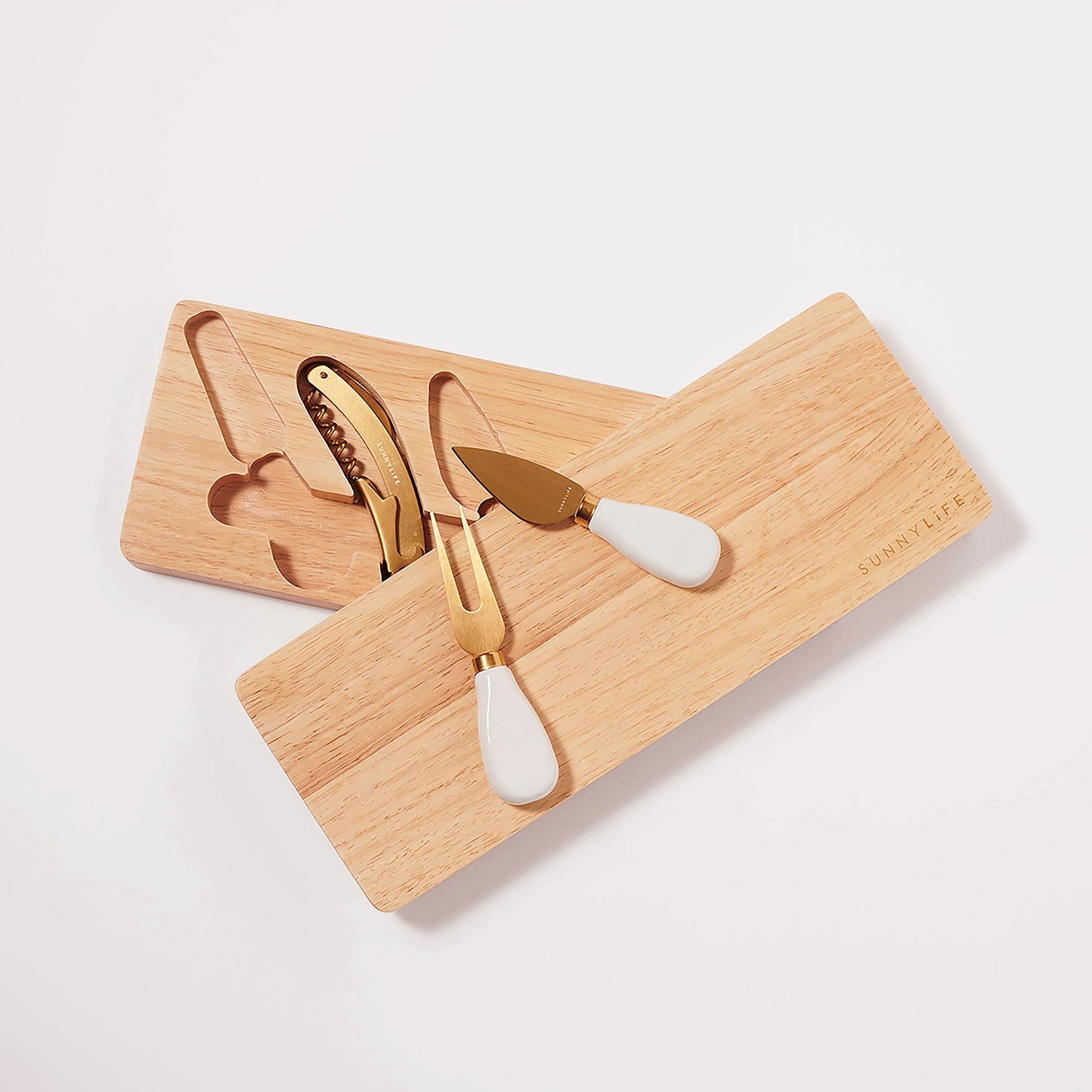 A travel cheese set consisting of a beige wooden board and gold-colored utensils, including a knife, spreader, and fork.