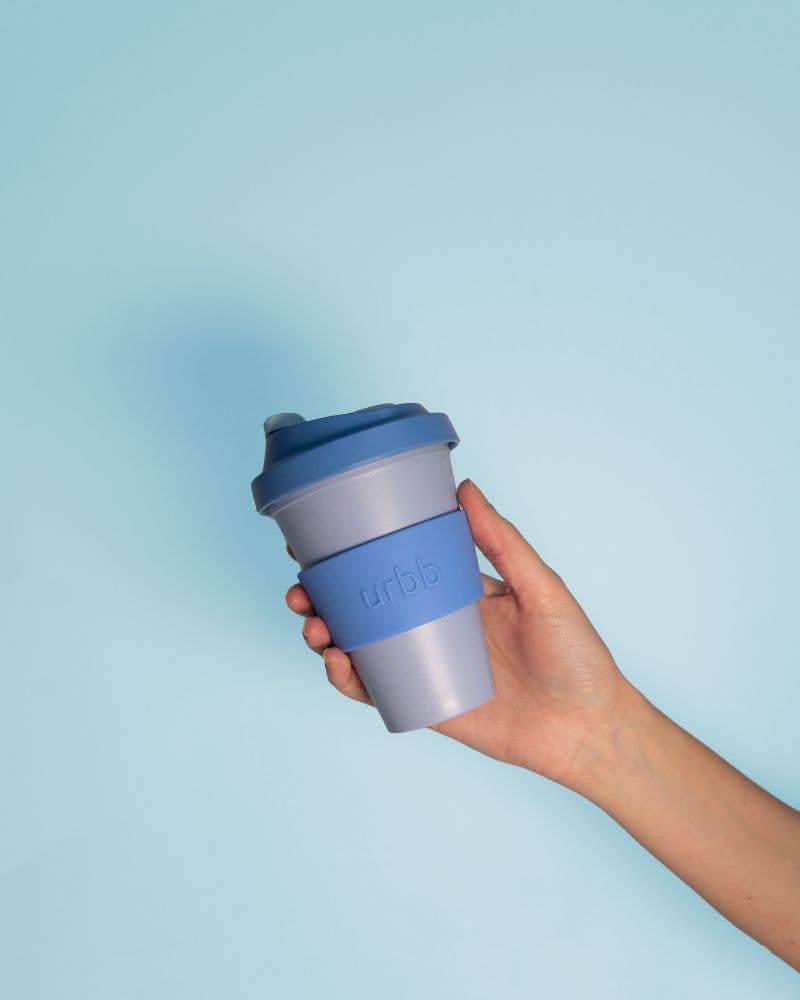 Hand holding a blue reusable coffee cup with a light blue background