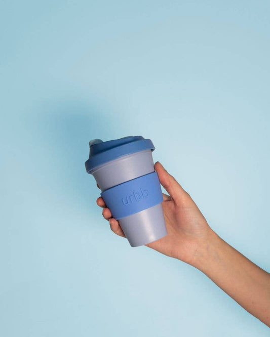 Hand holding a blue reusable coffee cup with a light blue background