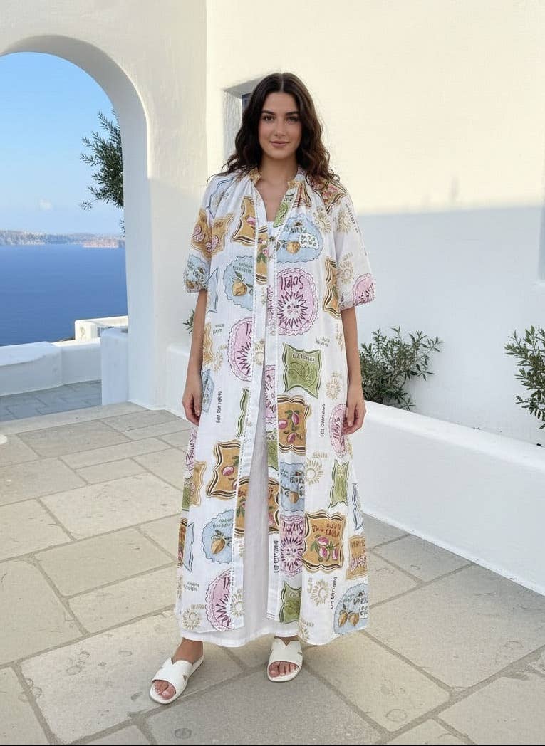 Woman in a floral dress standing in front of a white building with a blue sea view.